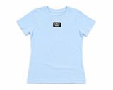 Lulu Mac women's light blue babydoll tee with short sleeves and black logo patch on chest, displayed as a flat lay on a white background.
