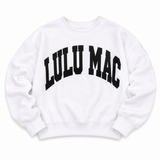 White Lulu Mac crewneck sweatshirt featuring oversized black puff "LULU MAC" lettering across the front with a relaxed fit and ribbed cuffs, displayed on a white background.
