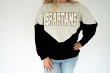 Spartans chenille varsity colorblock sweatshirt in heather gray and black with oversized white SPARTANS lettering outlined in purple and gold.