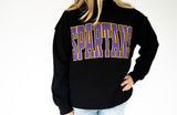Women’s black Spartans mock neck sweatshirt featuring oversized purple SPARTANS lettering with gold polka dot details and outline, perfect for game day and school spirit.