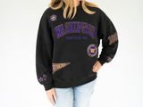 Woman modeling a black University of Washington Huskies mock neck sweatshirt with purple and gold Washington, Seattle WA, paw print, pennant, 1861, star, and W graphics, paired with light-wash jeans on a white background.
