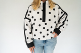 Women's Veveret white and black polka dot contrast half-zip pullover with black trim, front pockets, and relaxed fit.
