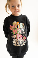 Child wearing a black sweatshirt with colorful text design on a white background