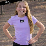Young girl wearing a purple 'LULU MAC' t-shirt with a blurred background