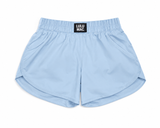 Lulu Mac youth light blue athletic shorts with elastic waistband and black logo patch, displayed as a flat lay on a white background.