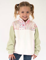 A young girl with blonde pigtails wearing a quarter-zip fleece pullover. The Simply Southern pullover features a light green body and sleeves, a white chest panel, and a pink and multicolor floral pattern across the shoulders and upper chest.