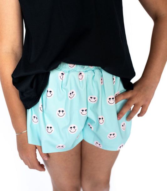 Bring on the smiles and sunshine! These adorable minty aqua shorts are sprinkled with the cutest pink smiley faces—complete with flirty lashes and chill palm tree vibes. But it gets even better... they’ve got built-in fitted shorts underneath, so your little one can cartwheel, climb, and conquer the playground worry-free! Breezy outer shorts with a fun all-over smiley print
Built-in fitted shorts for extra coverage and comfort
Soft elastic waistband for an easy, pull-on fit
Color: Aqua with pink smiley face