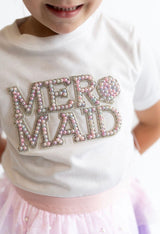 Child wearing a white shirt with 'MER MAID' in pearl and rhinestone letters on a white background