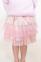 Pink and cream tulle skirt with pearls and a pink bow on a child with a white background